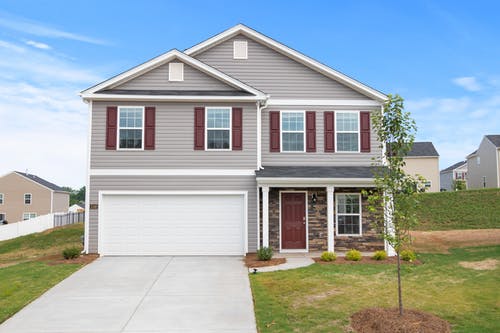 The front of a single-family home with a driveway and grass yard